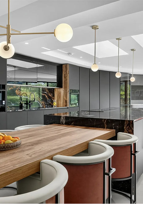 Contemporary grey kitchen with black marble waterfall island and wooden dining table